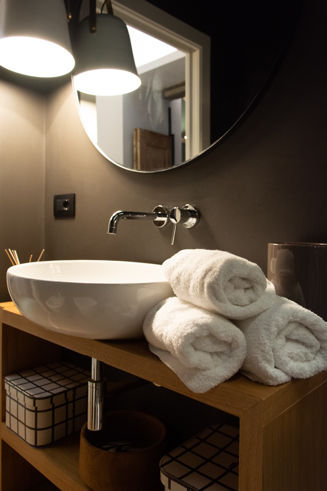 White vessel basin with wall-mounted tap and rolled towels