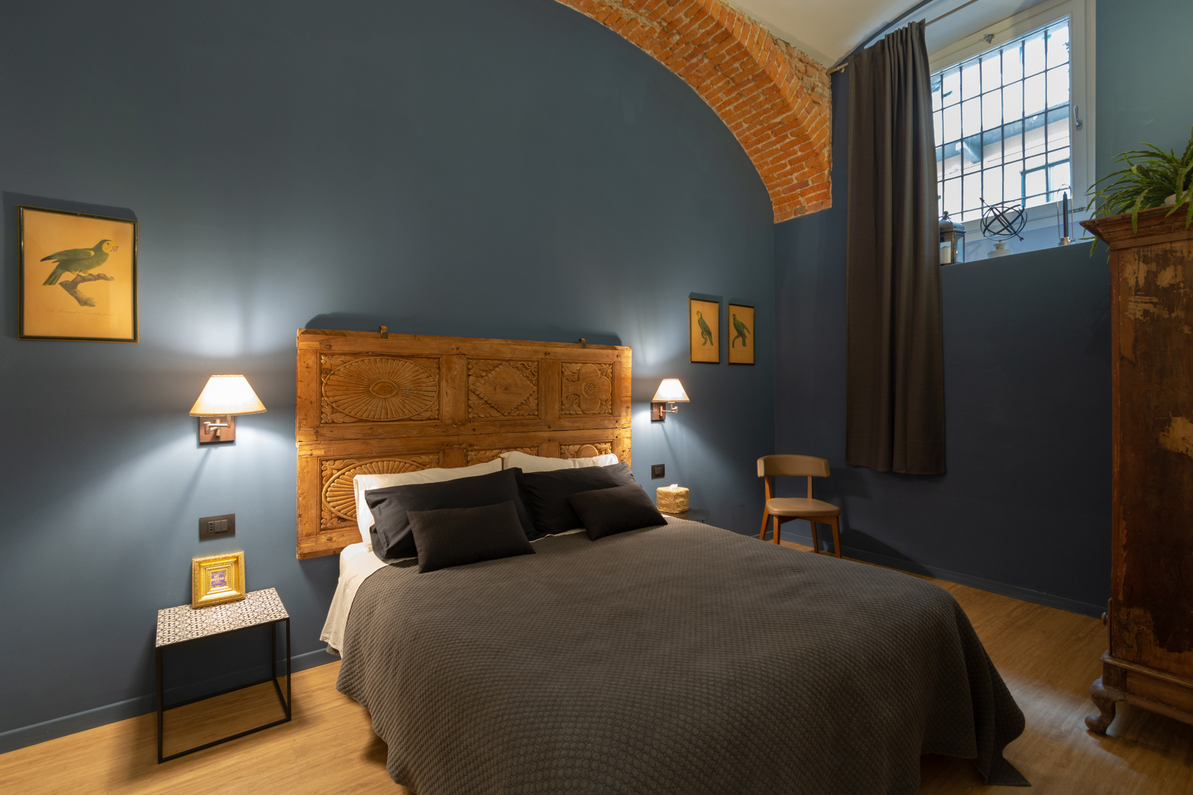 Master bedroom with carved wooden headboard, blue walls and brick vault