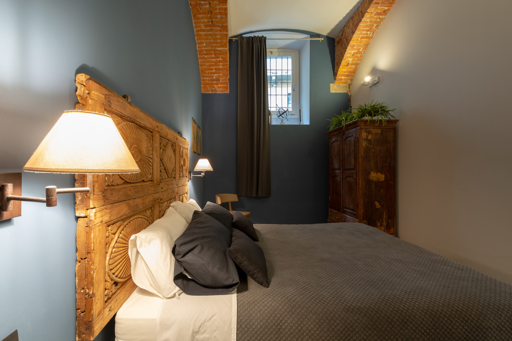Bedroom one with window, antique armoire and carved wooden headboard