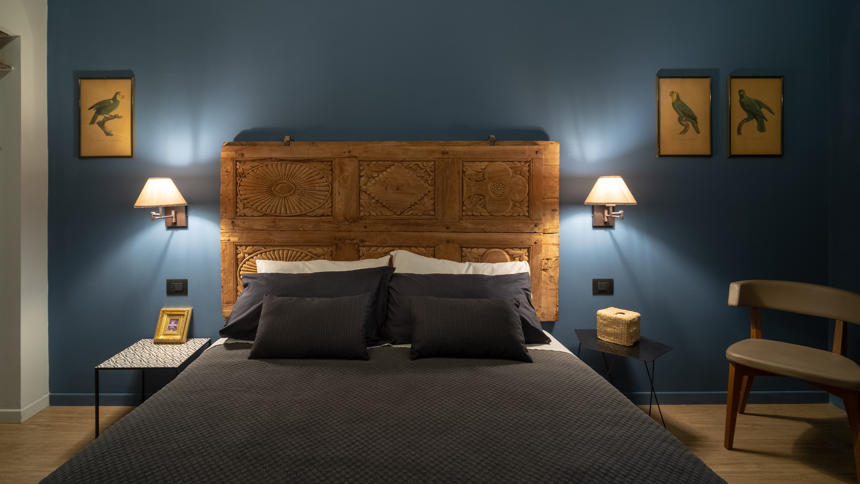 Double bed with carved headboard flanked by matching wall lamps
