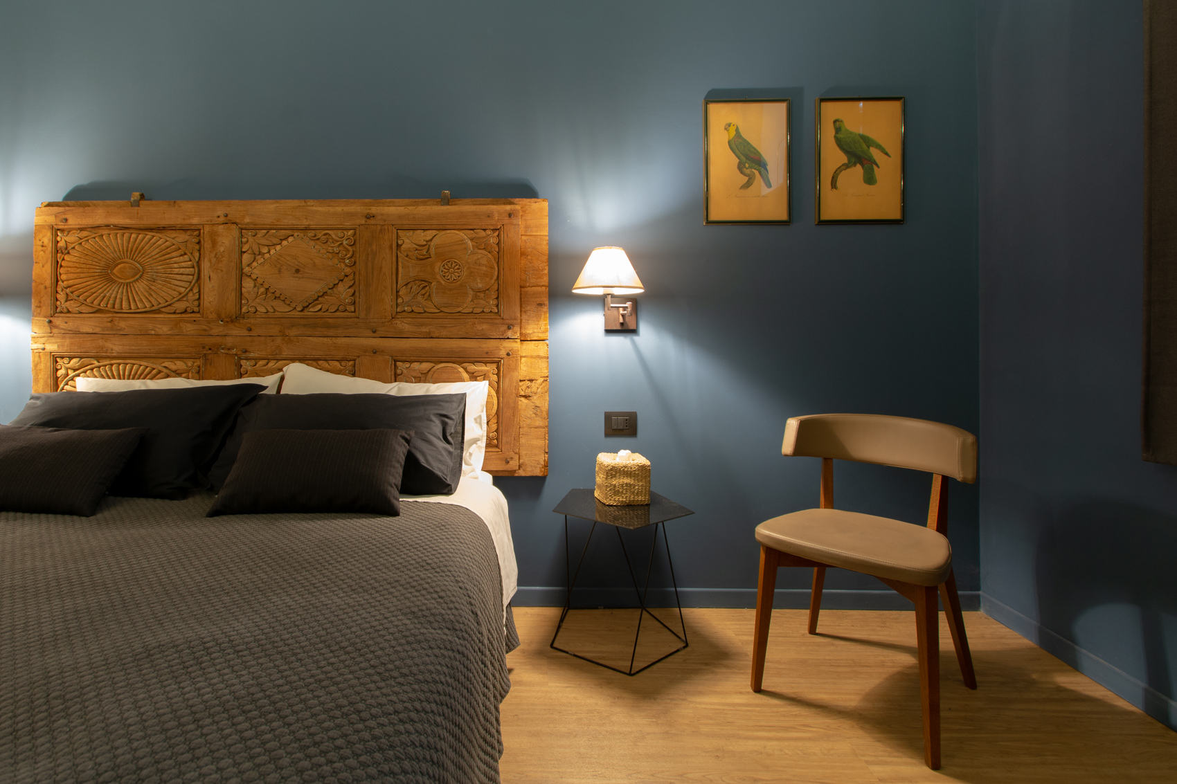 Bedroom one with reading chair, framed prints and deep blue walls