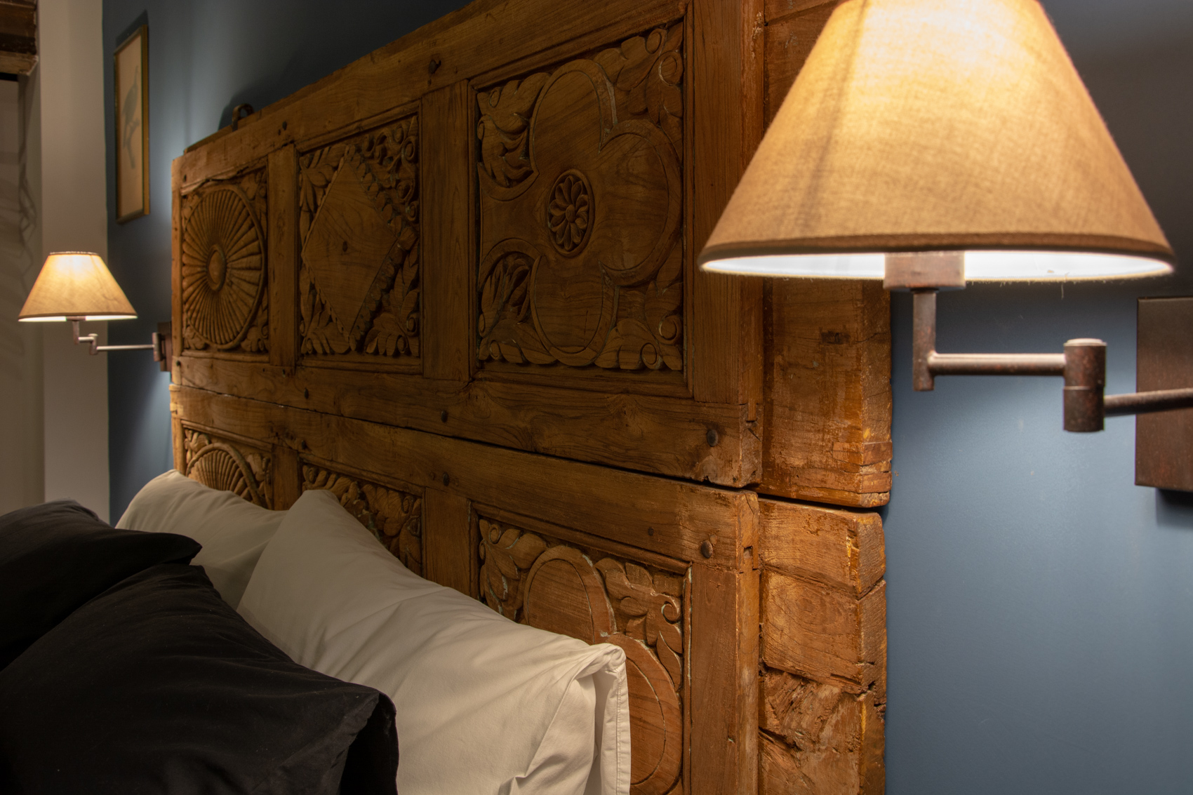 Detail of the carved wooden headboard and swing-arm wall lamp