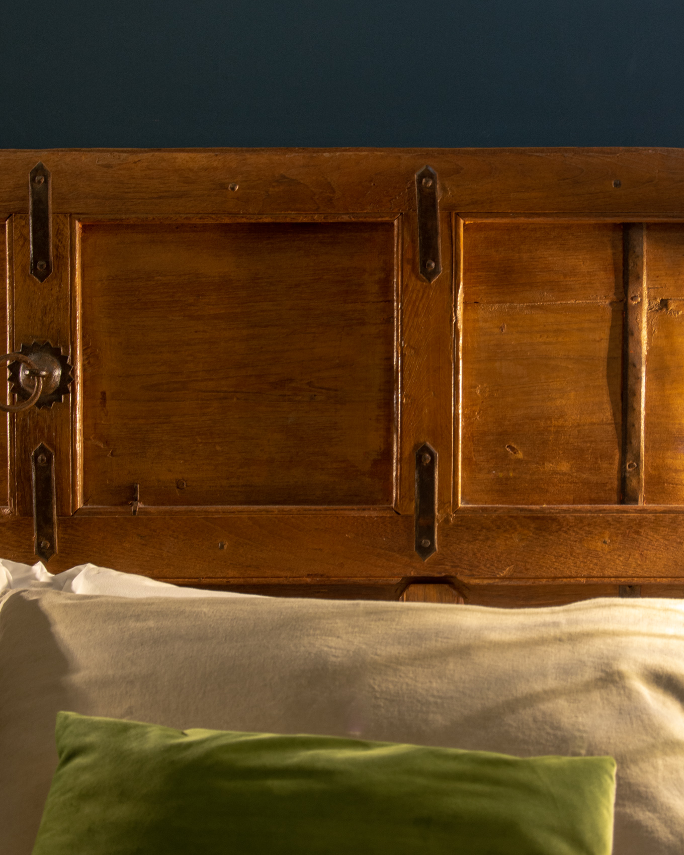 Carved headboard detail with green velvet cushion