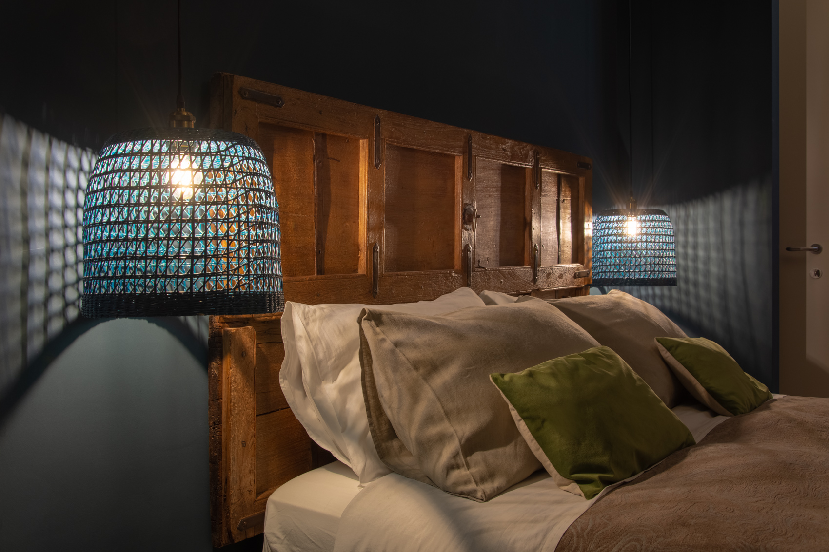 Bed with carved headboard and layered cushions in low light