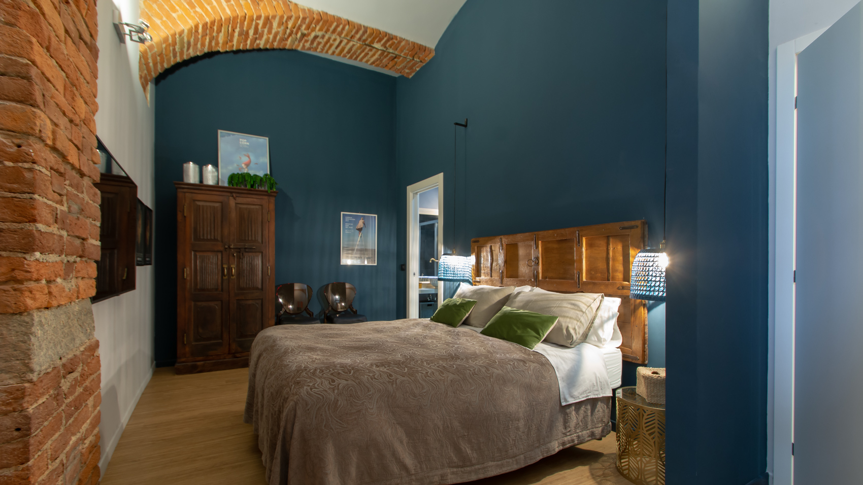 Second bedroom with exposed brick, armoire and green cushions