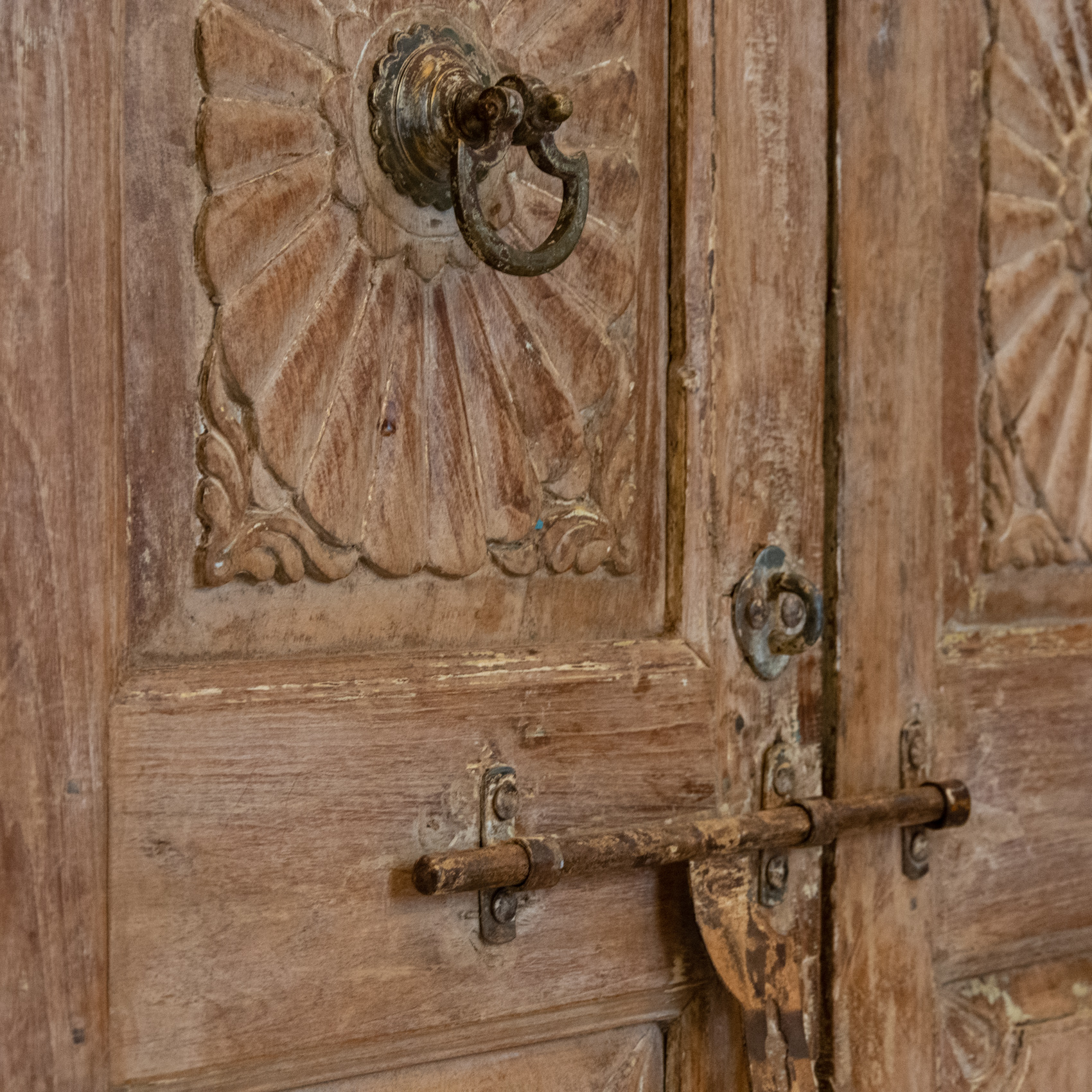 Detail of an antique carved wooden door with iron bolt
