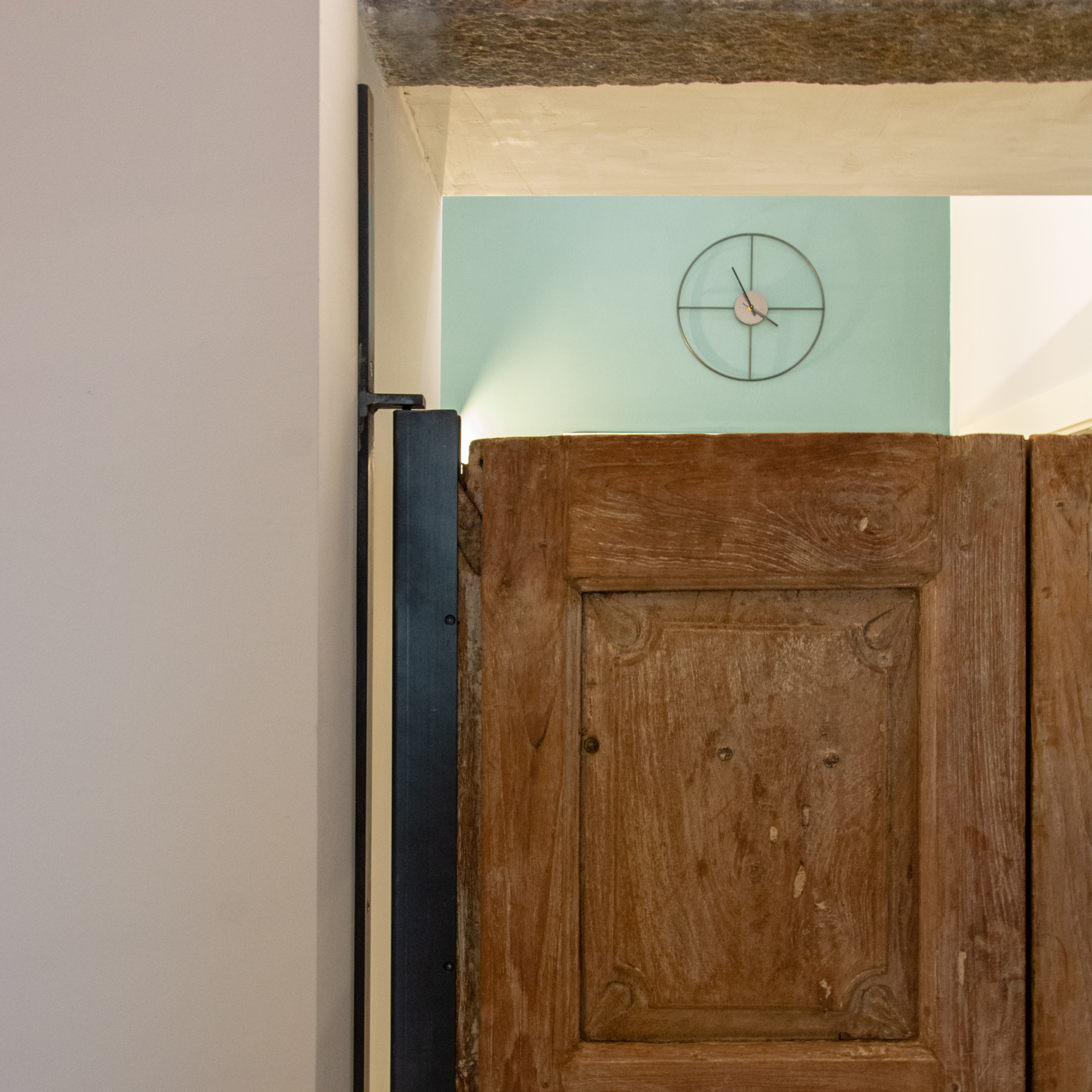 Antique wooden panel and wall clock against a sage green wall