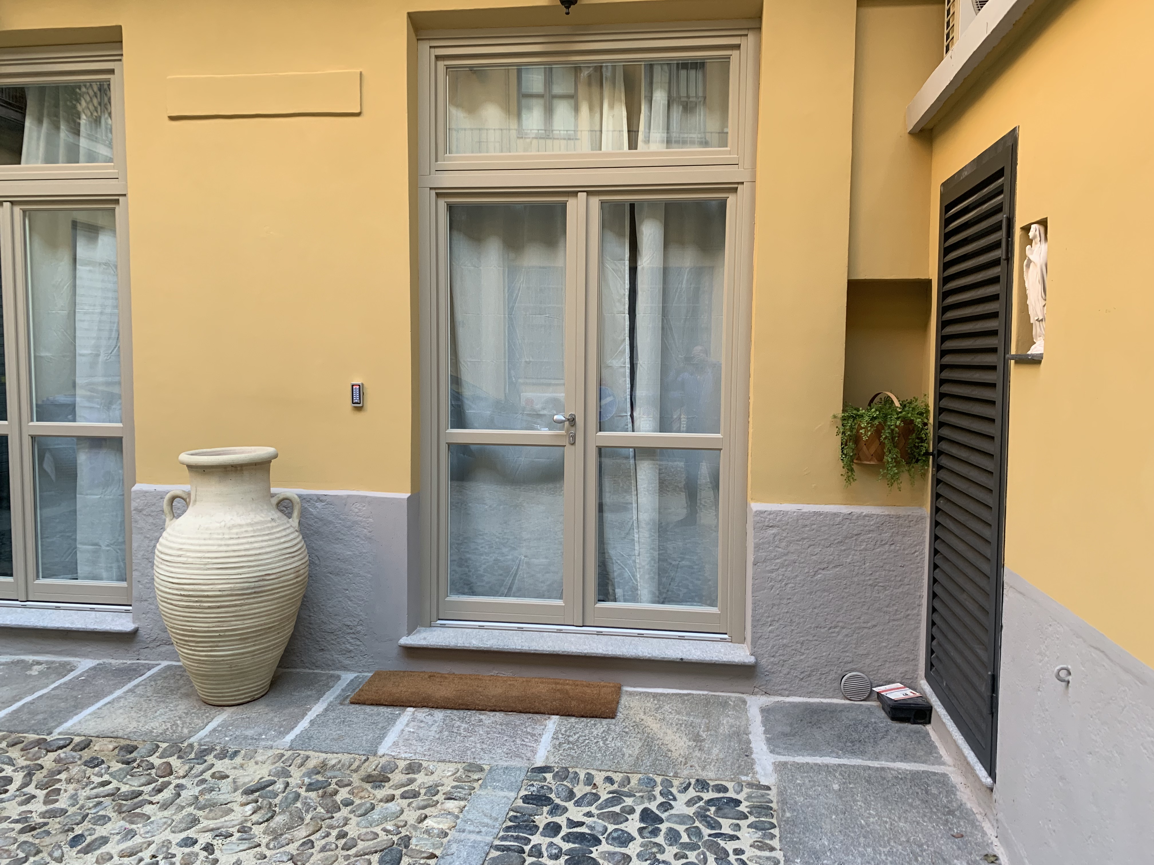 Casa Bellezia entrance in a historic Turin courtyard with terracotta vase