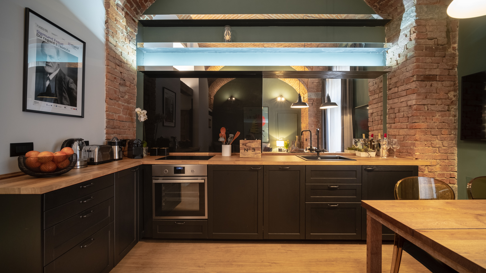 Fully equipped kitchen with dark cabinetry and exposed brick