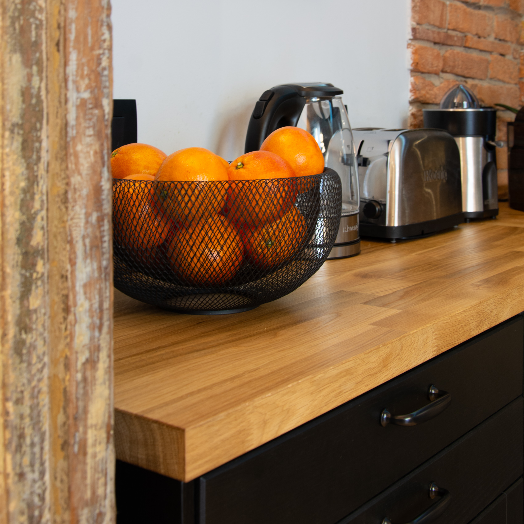 Wooden worktop detail with fresh oranges, kettle and toaster